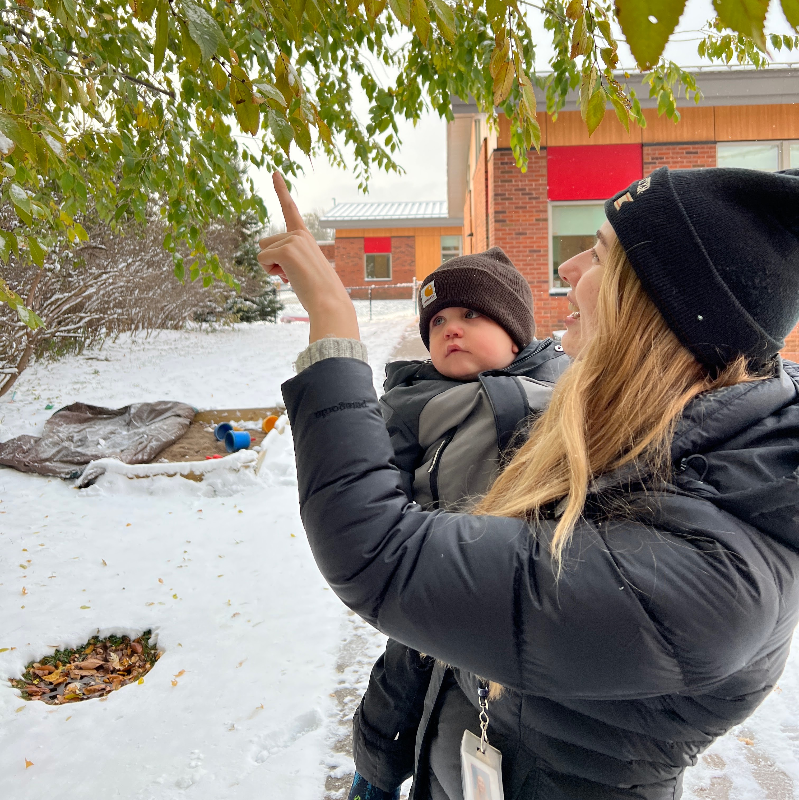 mom and baby looking at tree in winter